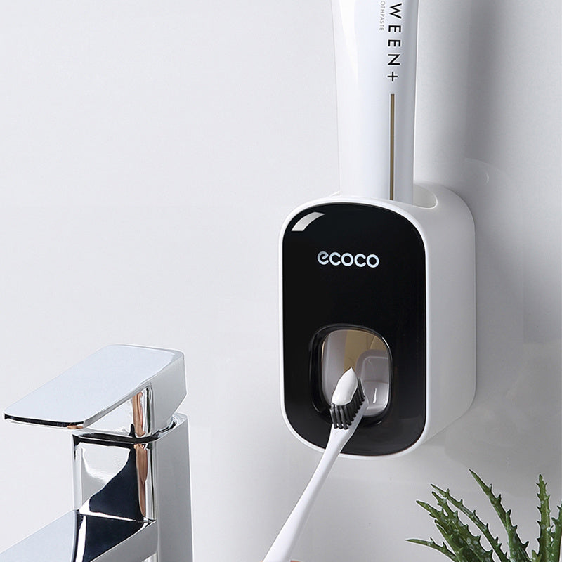 White toothbrush with black handle attached to a wall-mounted holder labeled 'ecoco' on a white background.